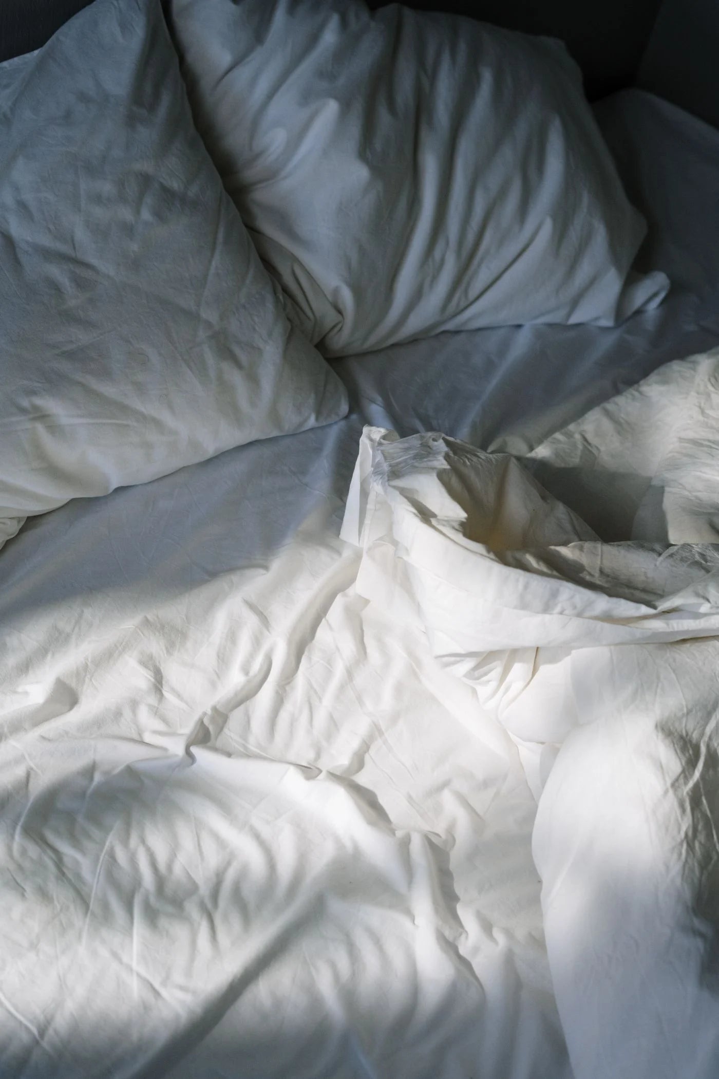 Real morning light falling across softly creased white bedding