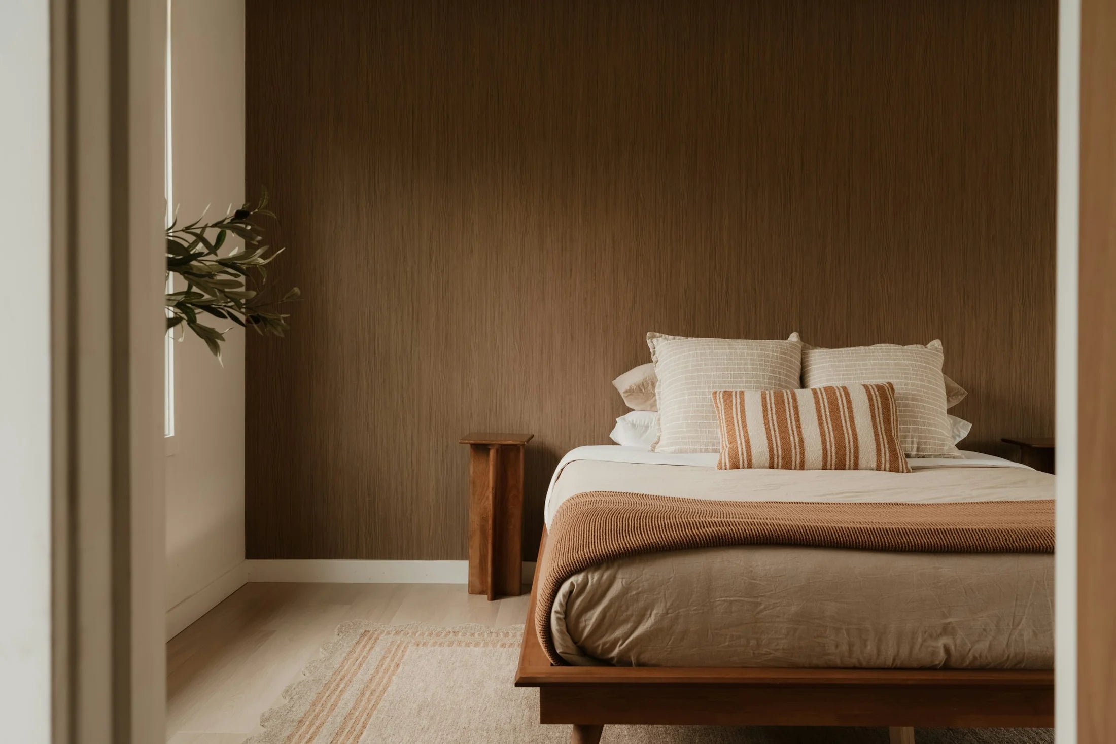 Bedroom inspiration: warm wood, textured walls and soft linen photographed through an open doorway